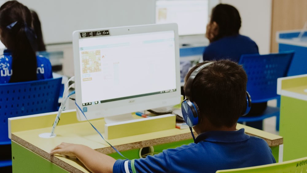 Aluno utilizando novas tecnologias na educação ajudando no aprendizado pelo computador